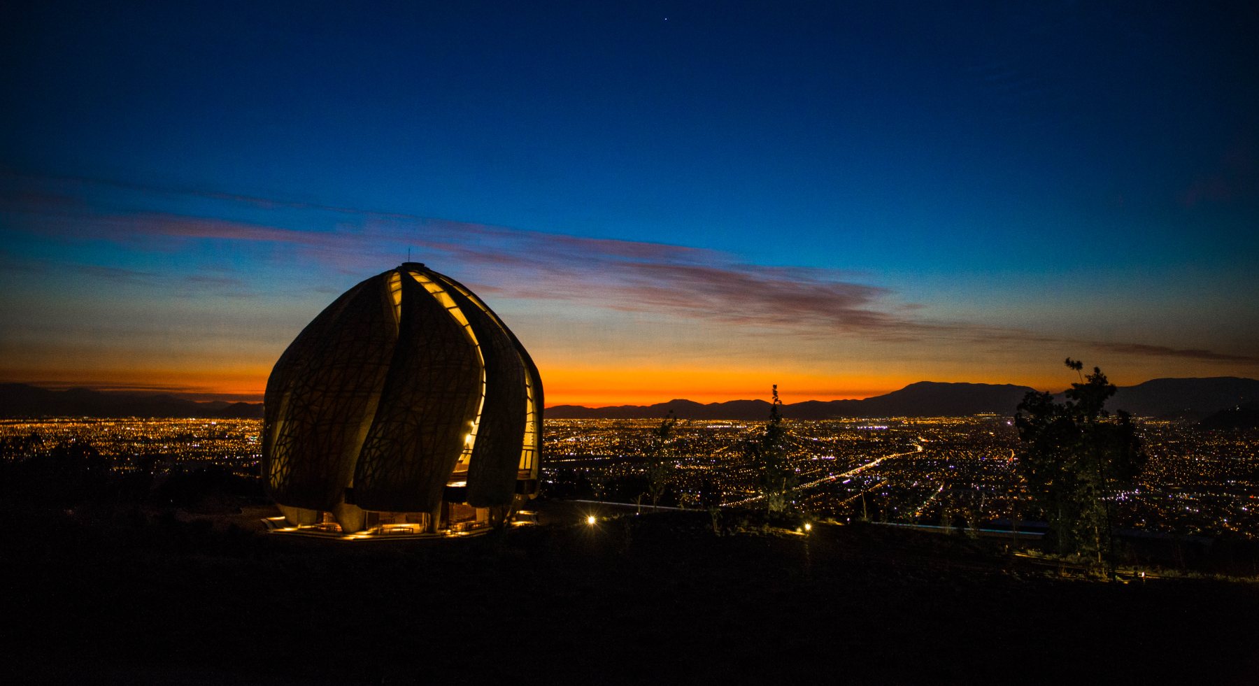El Templo Bahá’í iluminado al atardecer sobre las luces de Santiago